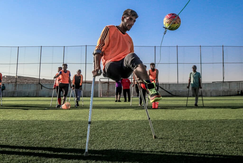 A football player with crutches hitting a ball. A football player with crutches hitting a ball.