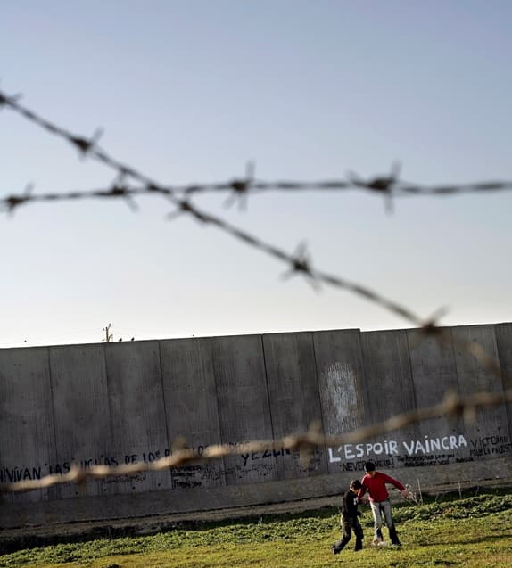 Two children play football in front of a concrete wall. Two children play football in front of a concrete wall.