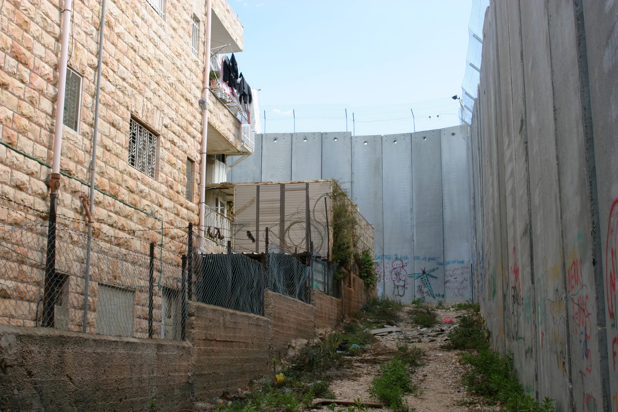 A high concrete wall next to an appartement building. A high concrete wall next to an appartement building.