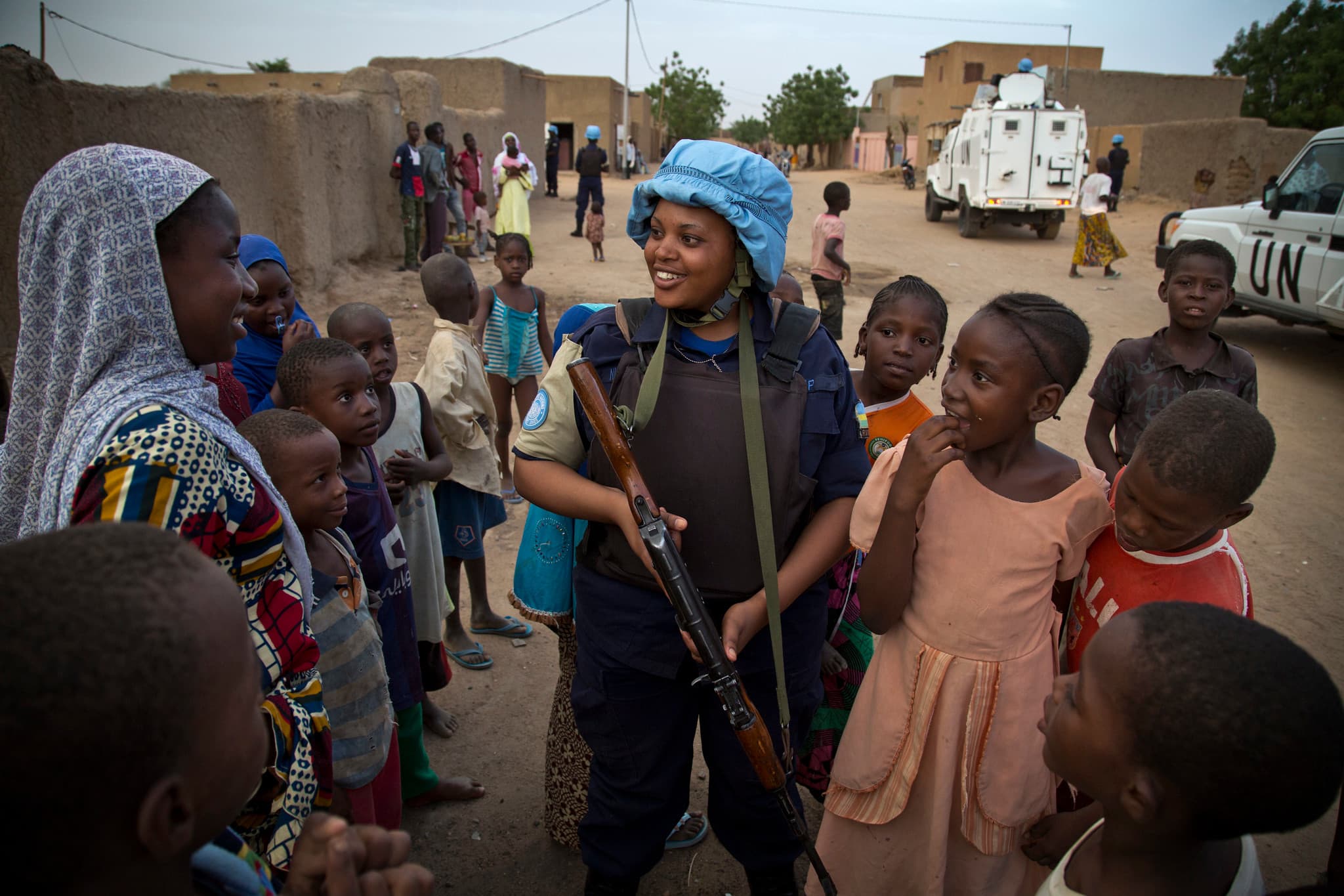 A female soldier with a blue helmet surrounded by women and girls. A female soldier with a blue helmet surrounded by women and girls.