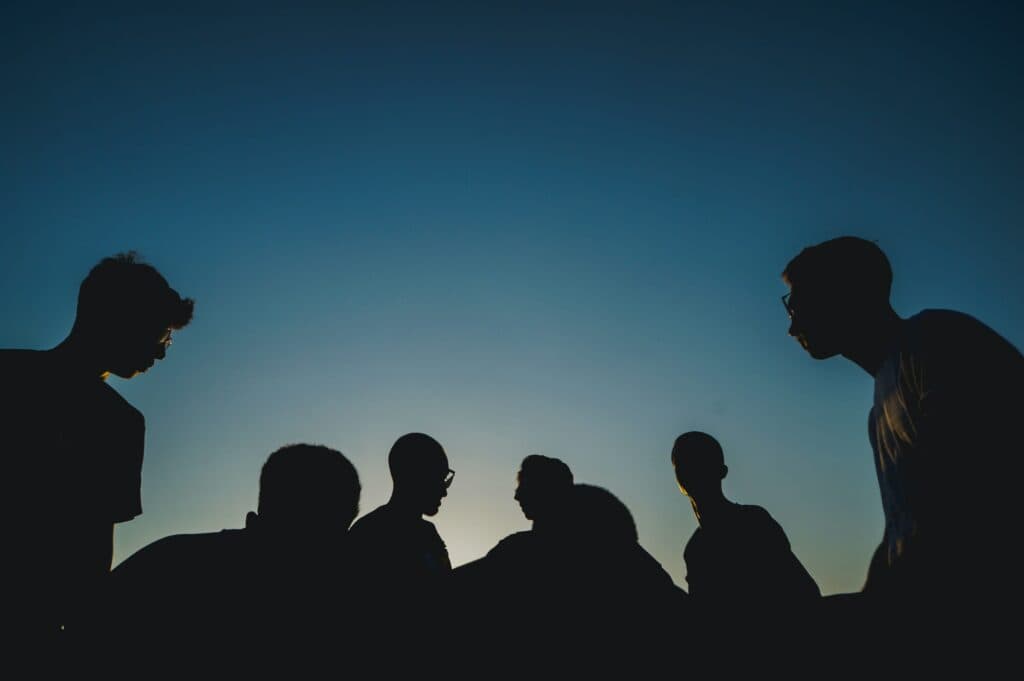 Silhouettes of people in front of a blue sky.